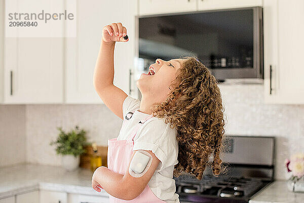 Little girl with diabetes about to put a berry in her mouth