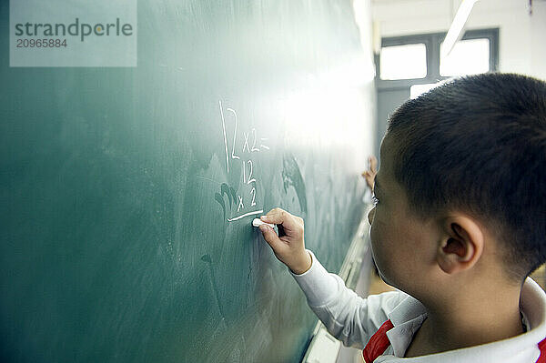 Young students practicing math on a chalkboard.