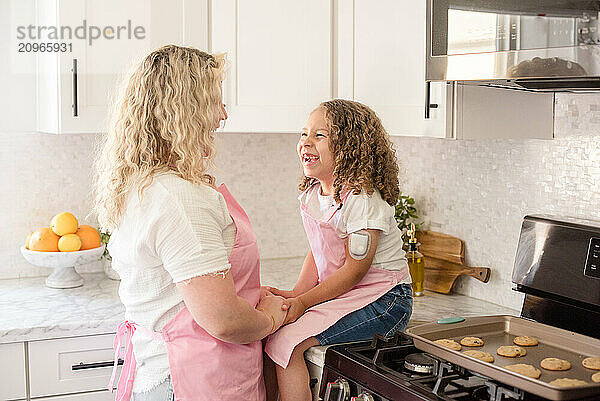 Daughter with diabetes sitting on the counter in the kitchen laughing