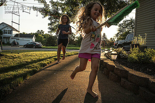 Young sisters playing tag outside on sunny summer evening