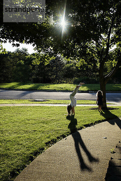 Young sisters doing hand stand outside on sunny day