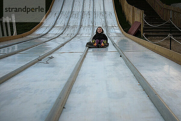 Happy young girl riding down giant slide