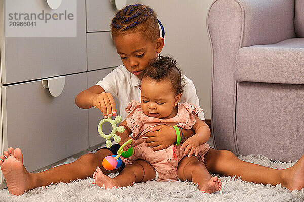 Caring brother playing with baby sister on the floor