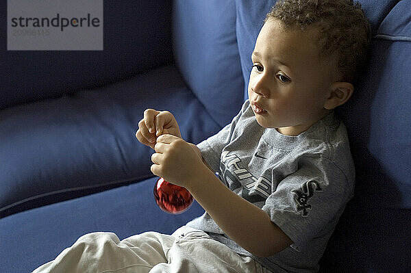 Portrait of a young boy holding a red ornament