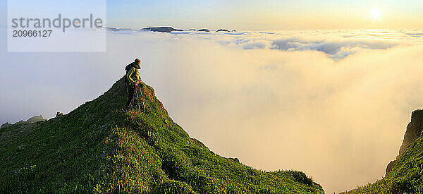 Hiker watching sunset above the clouds on Kalfatindar  Hornstrandir Peninsula  Westfjords  Iceland