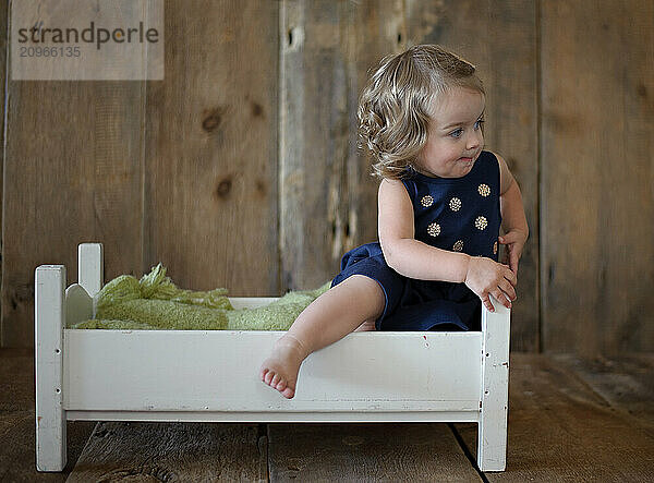 Profile of beautiful toddler sitting in small white bed