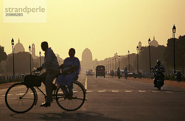 Men on bicycle in front of the Capital building in New Delhi  India  at sunset.