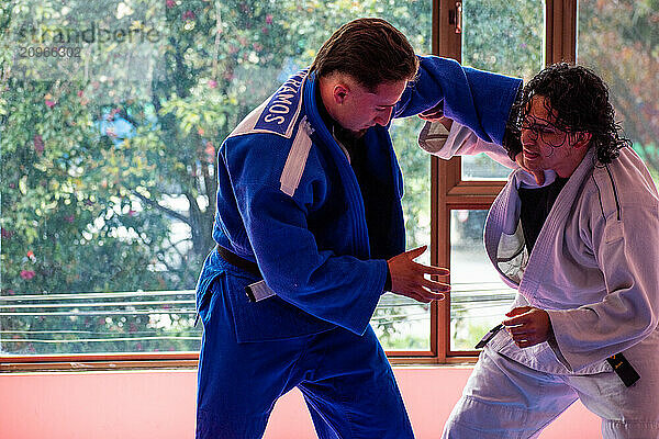 Judo fighters fighting in dojo with big windows at background