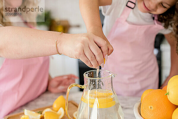 Close up of Mother and daughter squeezing a lemon in the pitcher