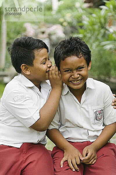 A group of young boys smiling and playing on an open field and climbing a tree