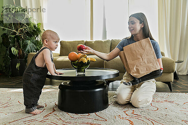 Young woman with prosthesis puts fruits with baby boy