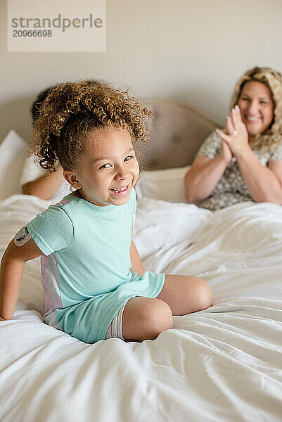 Little girl smiling and sitting on bed