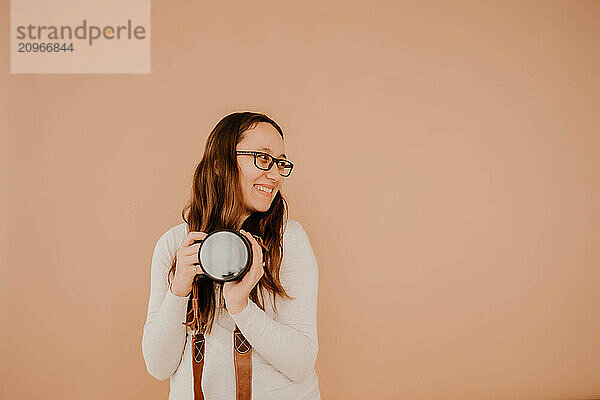 Smiling Hispanic young female photographer holding camera