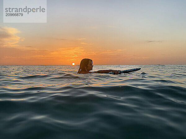 Profile of young girl on paddle board Gulf of Mexico at sunset