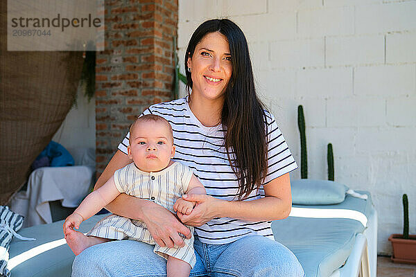 Young mother holding her baby and smiling in a terrace