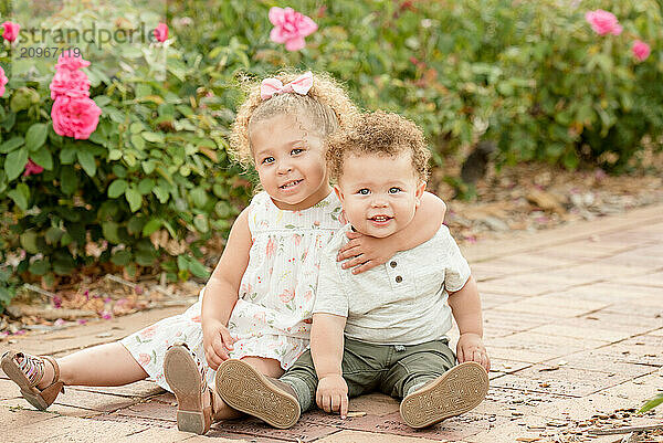 Sister hugging brother sitting in a garden