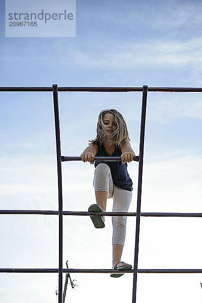 Young girl climbing jungle gym at park