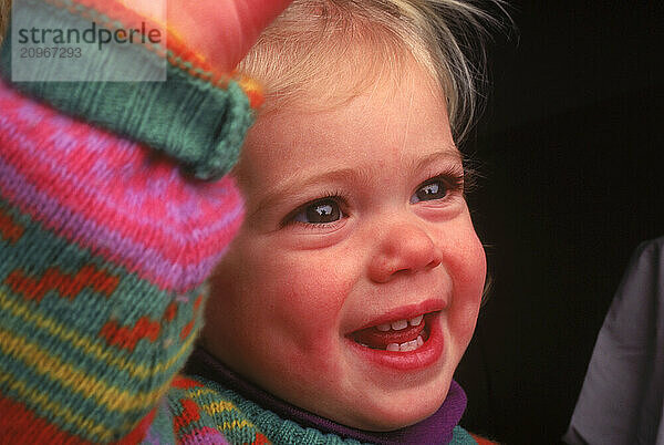 Close-up of a little girl with bright eyes smiling.