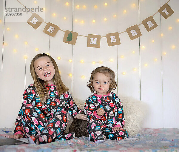 Beautiful young sisters in holiday pajamas Christmas backdrop