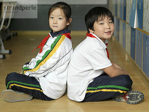 Two classmates sitting indian style on the floor.