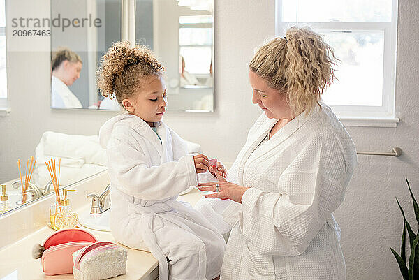 Daughter is filing mothers nails in the bathroom