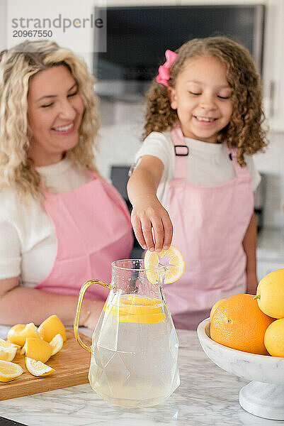 Little girl putting a lemon slice on the side of the pitcher