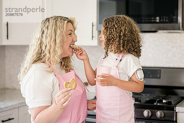 Daughter with diabetes feeding mother a cookie in the kitchen