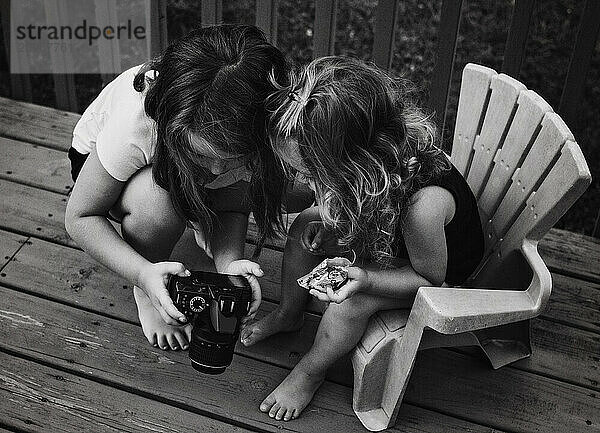 Young sisters taking photographs in back yard