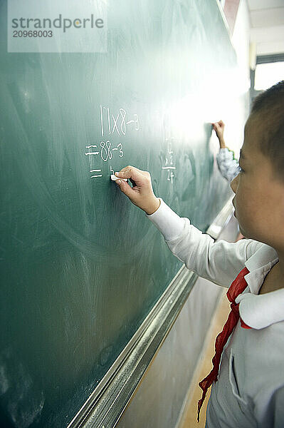 Young students practicing math on a chalkboard.