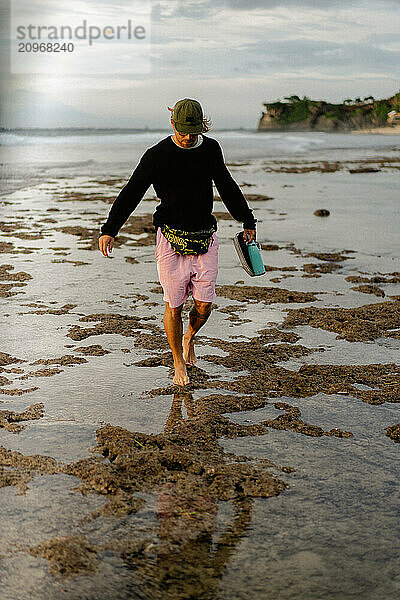 A young man walks along the beach in Bali.