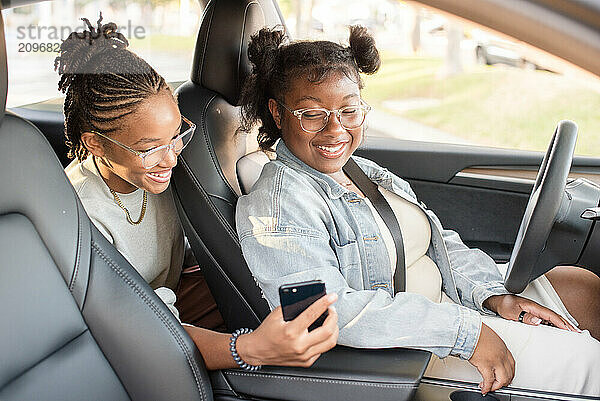 Young women looking at a phone in a car