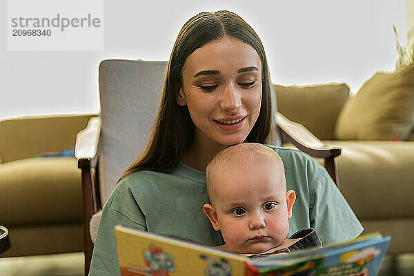 Young woman with prothesis reads book to her baby son