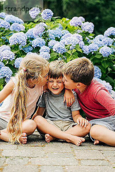 Three kids sitting  two kissing the one in the middle