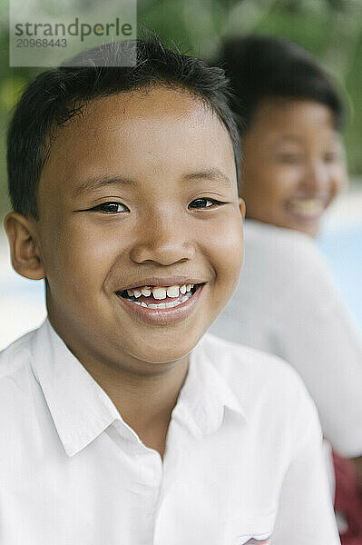 A group of young boys smiling and playing on an open field and climbing a tree