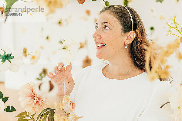 Woman smiling among white and soft-colored flowers  looking joyful