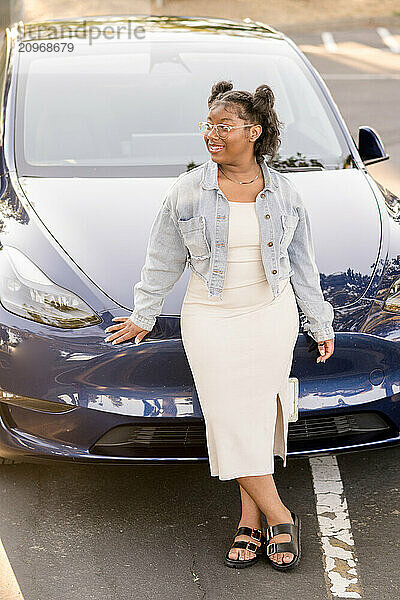 Young adult leaning against front of car