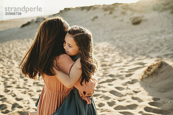 Happy Mother daughter hugging smiling beach summer sunset