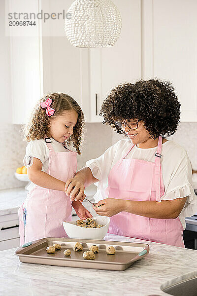 Biracial Sisters making cookies together in the kitchen