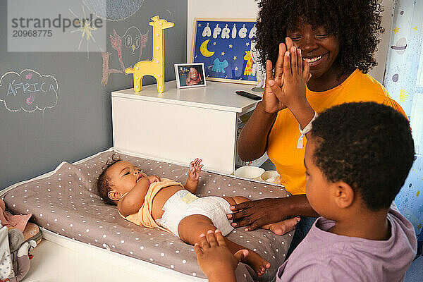 Happy family changing baby's diaper on changing table