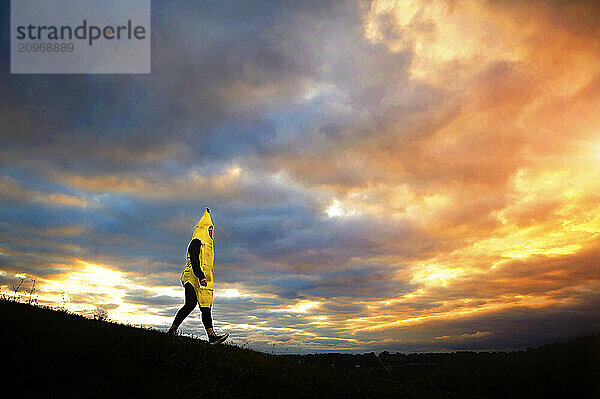 Teenager in banana costume walking down hill sunset