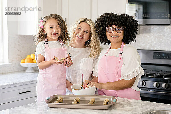 Mother and daughters smiling at the camera in the kitchen