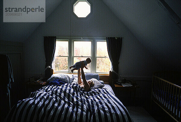 A mother playing with her baby  lying on a bed.