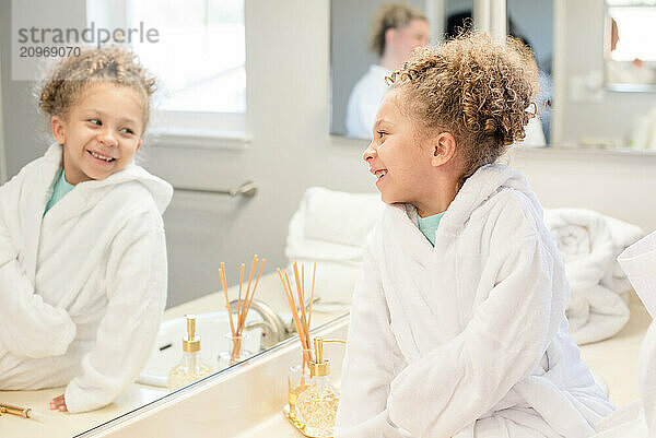 Little girl is looking at her reflection in the mirror