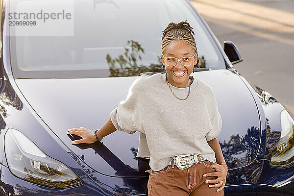 Young lady leaning against car smiling