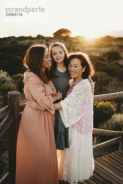 Three generations hugging women mom grandma girl beach sunset Spain