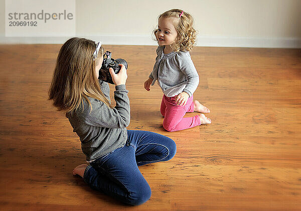 Young sisters taking pictures of each other indoors