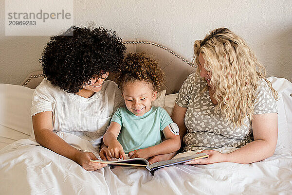 Mother reading with daughters in bed