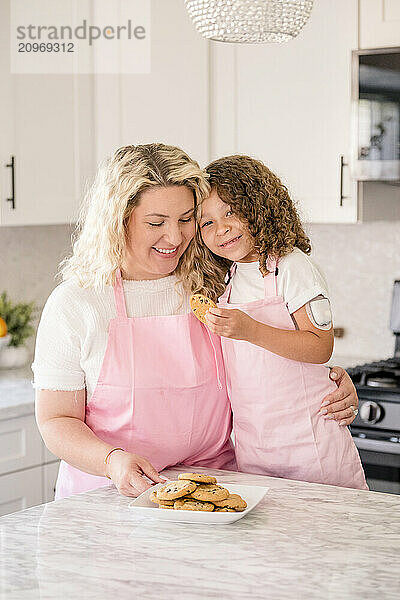 Mother holding daughter while daughter is holding a cookie