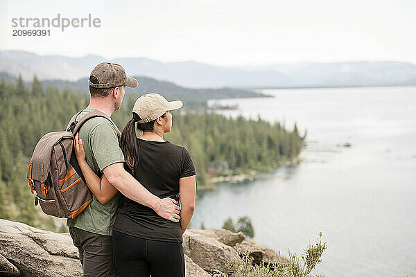 Hiker couple putting their arms around each other looking at the view