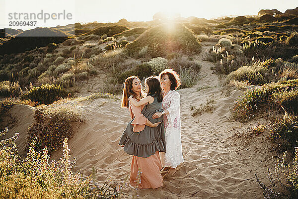 Three generations of women dancing at beach on summer day